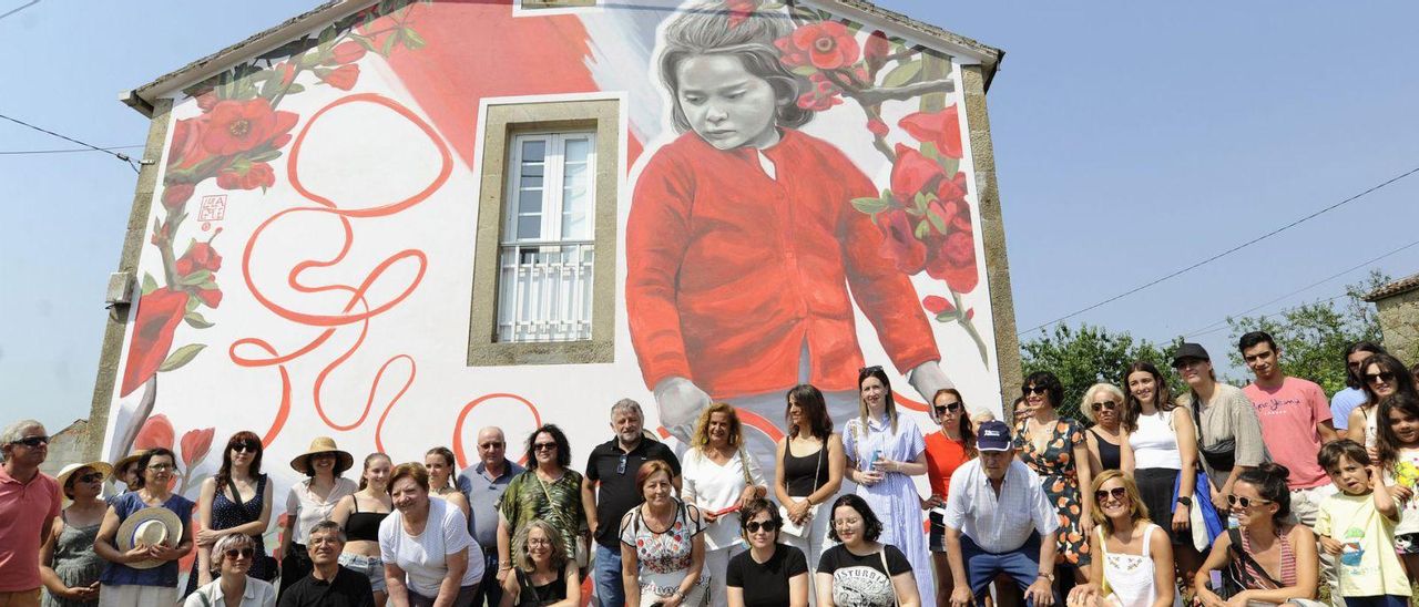 Vecinos, artistas y miembros del programa visionando los murales, ayer, en Cortegada.