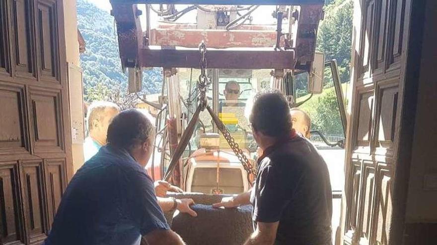 Vecinos de Nembra, ayer, transportando la pila al interior de la iglesia.