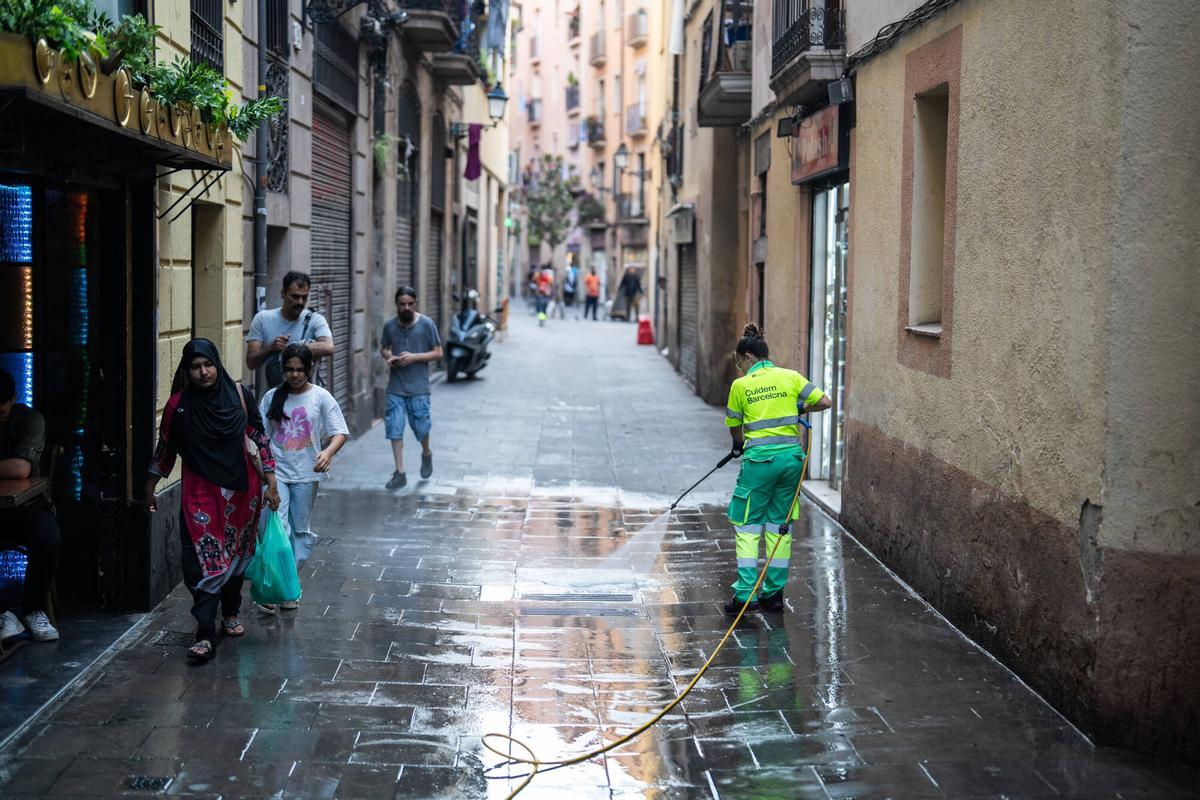 Barcelona. Jeffrey, propietario del bar Never, en la calle Cera 17 del barrio del Raval, retira con un carro de la compra las bolsas de basura acumuladas frente a su establecimiento antes de abrir el local, una situación que denuncia como habitual cada tarde. 29 de julio de 2026. Sociedad. AUTOR: ZOWY VOETEN