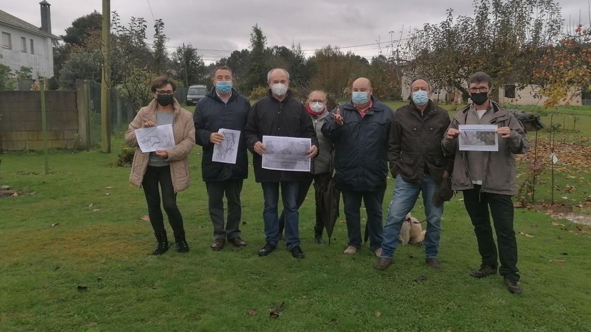 Un grupo de afectados posan con los planos en el punto por el que pasaría el vial, entre dos casas.