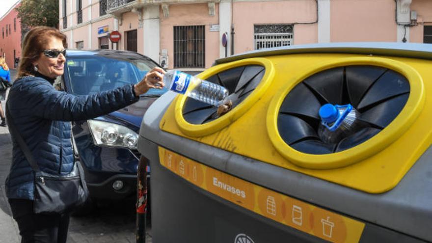 Una vecina introduce residuos en un contenedor de reciclaje.