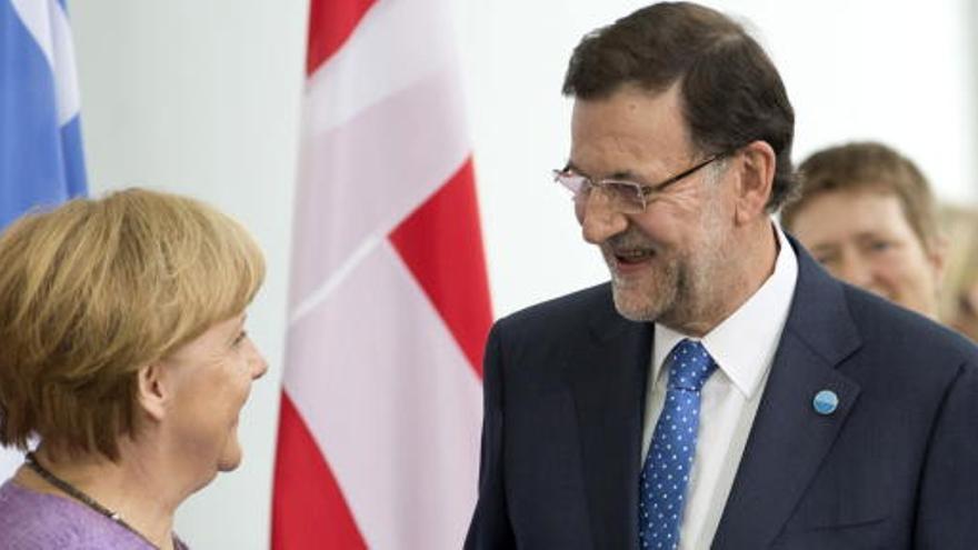 Merkel y Rajoy se saludan.