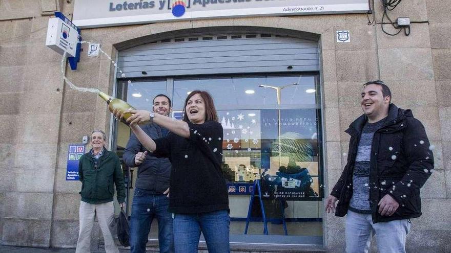 Amelia Losada, con el cartel, brinda con algunos clientes de su cafetería.