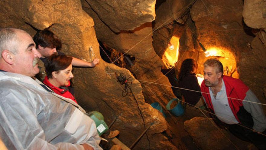 Camilo Montes y Mercedes Álvarez, atentos a las explicaciones de Marco de la Rasilla en el interior de la cueva de El Sidrón.