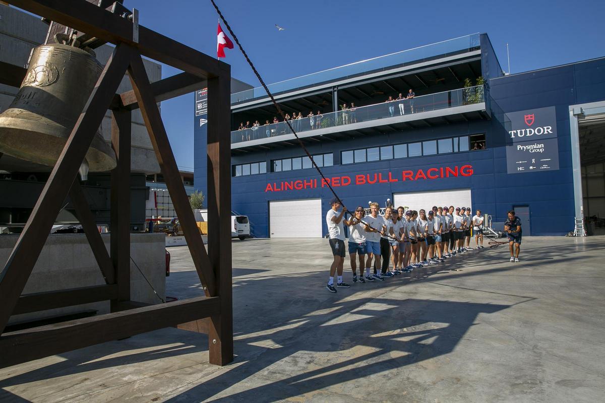 Las candidatas y los jóvenes del equipo suizo Alinghi Red Bull Racing de la Copa América de vela tocan la campana en la salida del AC75 a entrenar en el Port Vell.