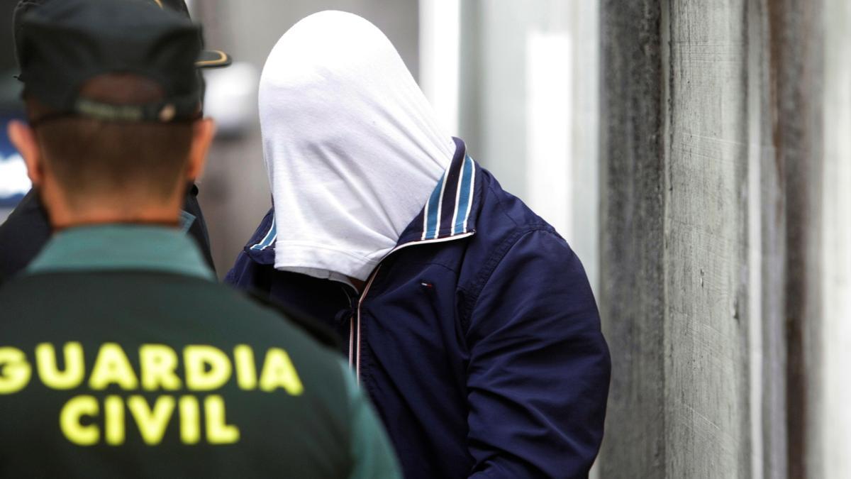 Un Guardia Civil observa a un detenido acusado de homicidio.