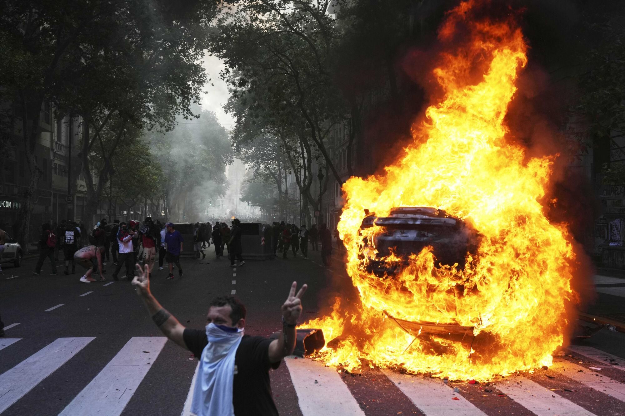 Protesters surround a burning car during a demonstration by soccer fans and retirees demanding higher pensions and opposing austerity measures implemented by Javier Milei's government in Buenos Aires, Argentina, Wednesday, March 12, 2025. (AP Photo/Rodrigo Abd). EDITORIAL USE ONLY/ONLY ITALY AND SPAIN
