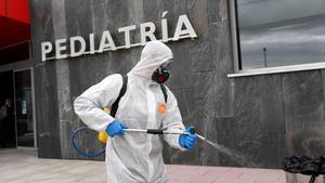 Un miembro de la Unión Militar de Emergencias desinfecta un acceso al Hospital Universitario Central de Asturias para combatir el coronavirus.