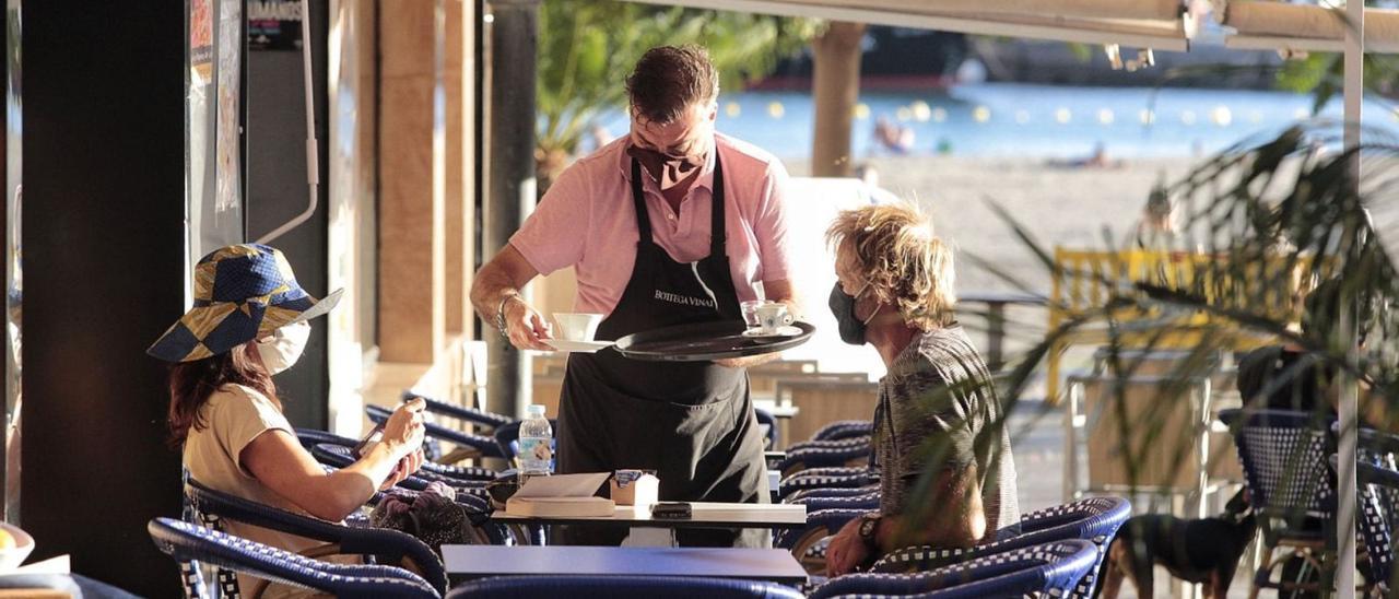 Un camarero sirve a dos turistas en Los Cristianos.