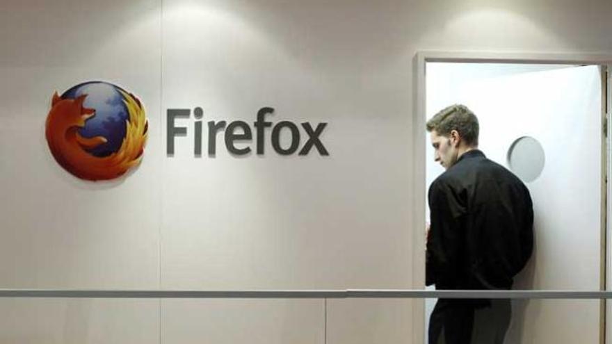 Un hombre pasa al lado del logo de Firefox.