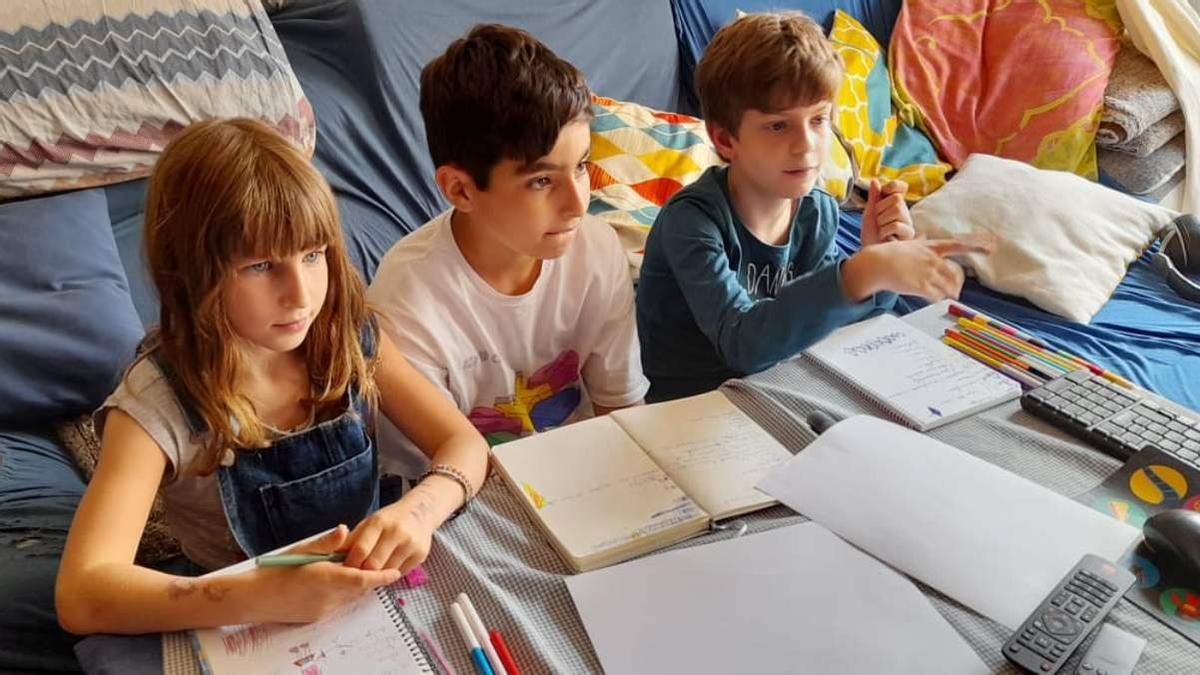 Tres niños que participan en 'Los mitos de la Antigua Grecia' siguen atentamente las instrucciones