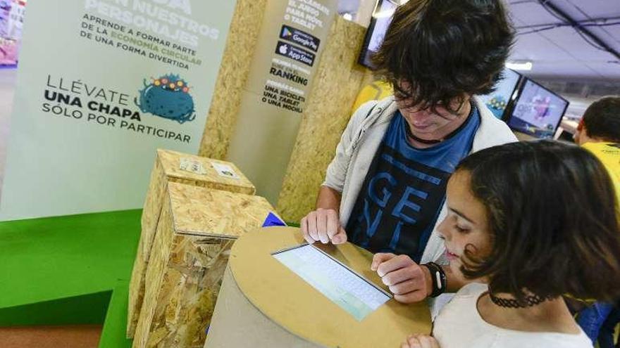 Dos niños juegan con el videojuego &quot;Recyrcle&quot; en el stand de Cogersa.