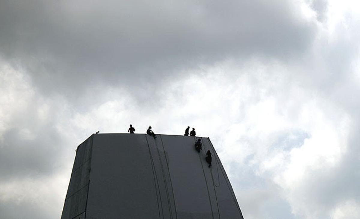 Les siluetes dels treballadors es retallen contra el cel mentre netegen un edifici construït recentment a Singapur.