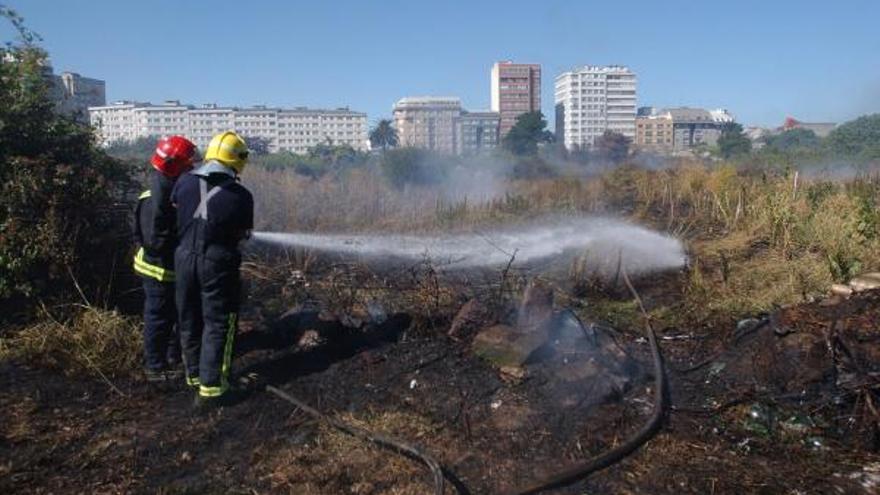 Los bomberos trabajan en la extinción de un incendio en una parcela de Vioño.