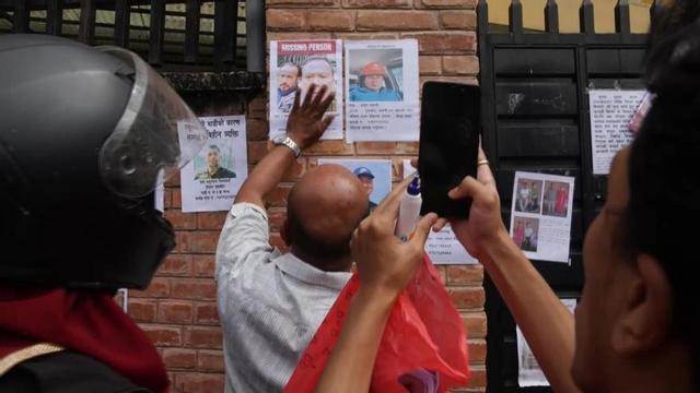 Nepalesos col·loquen fotografies fora del dipòsit de cadàvers per aconseguir identificar els morts per la riuada