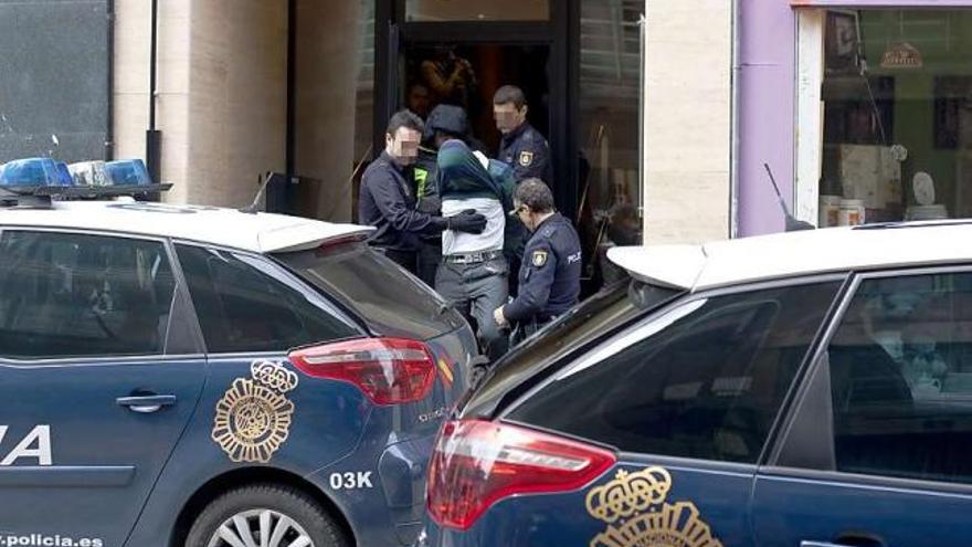 Uno de los detenidos se cubre al salir del portal.