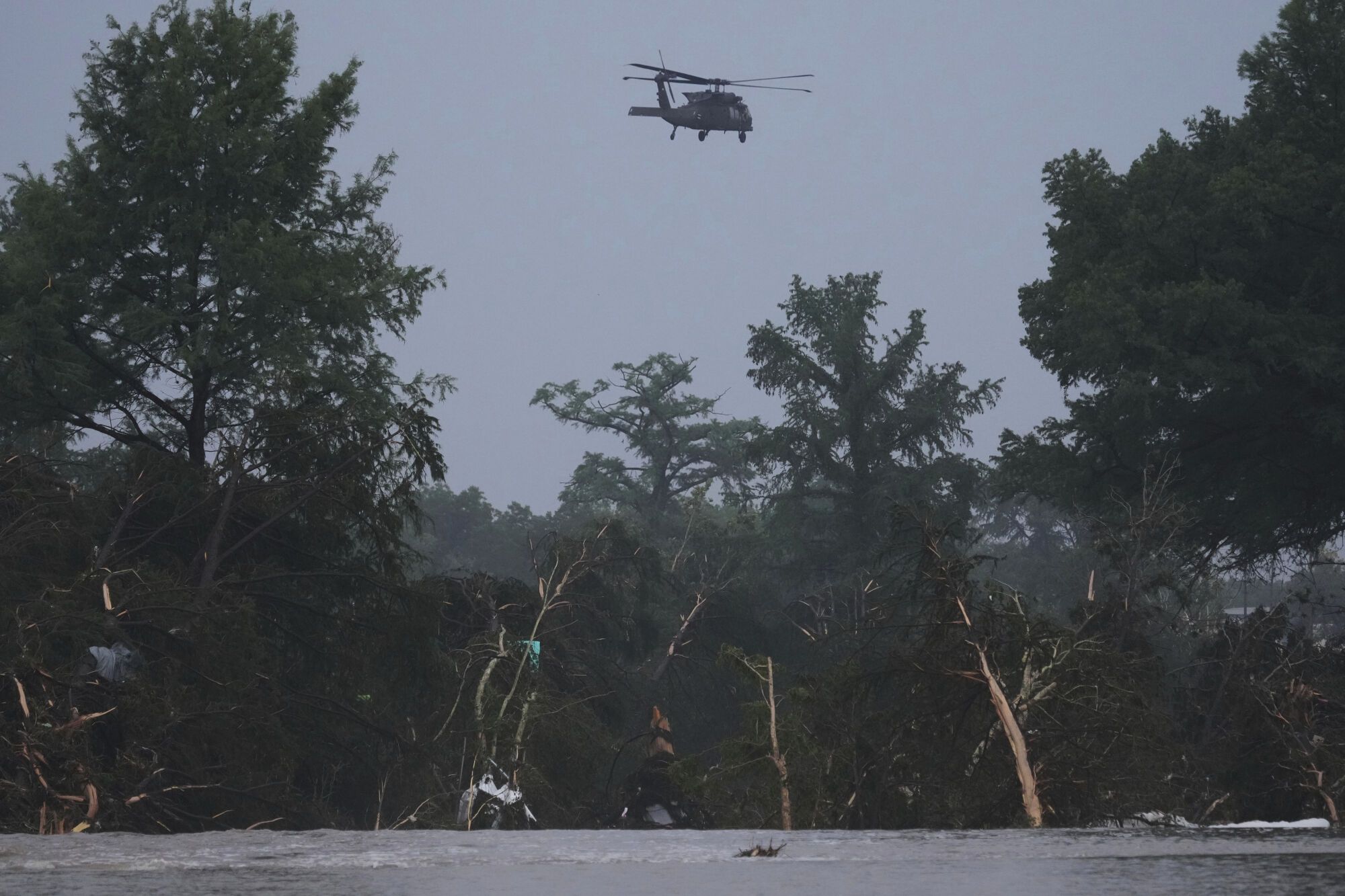 A helicopter flies over the Guadalupe River after a flash flood swept through the area, Friday, July 4, 2025, in Kerrville, Texas. (AP Photo/Eric Gay)