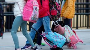 Niños con mochilas llegando al colegio.