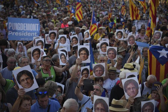 Manifestantes portan carteles con la cara de Puigdemont.