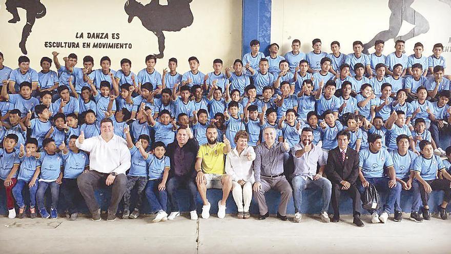 Sergio Álvarez, de amarillo en el centro, posa con los niños y responsables de la escuela.