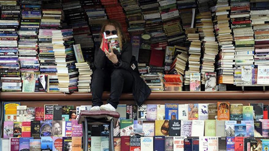 Una joven lee un libro en un quiosco callejero. // Reuters