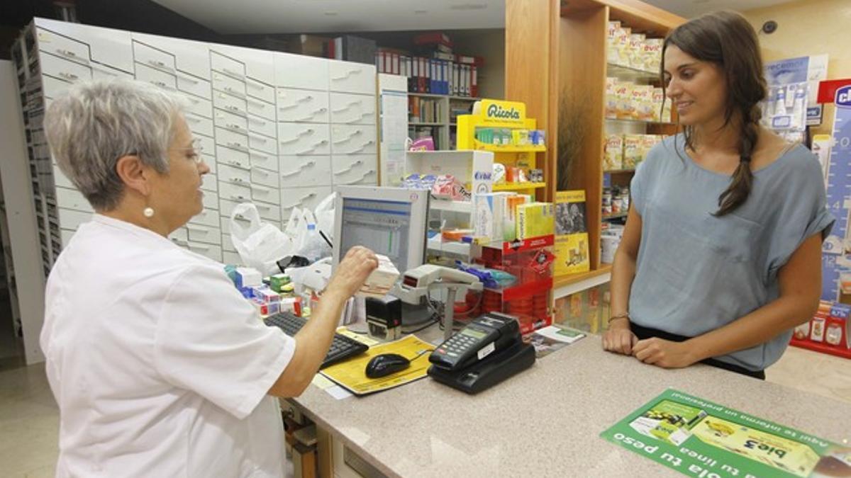 Una farmacéutica dispensa un medicamento a una clienta, el pasado septiembre, en Santa Coloma de Gramenet.