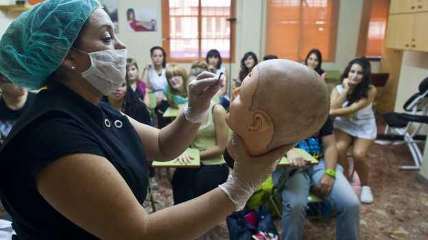 Una profesora del curso de tanatoestética de la academia Inespa de Elche explicando algunas técnicas a los alumnos durante una clase.