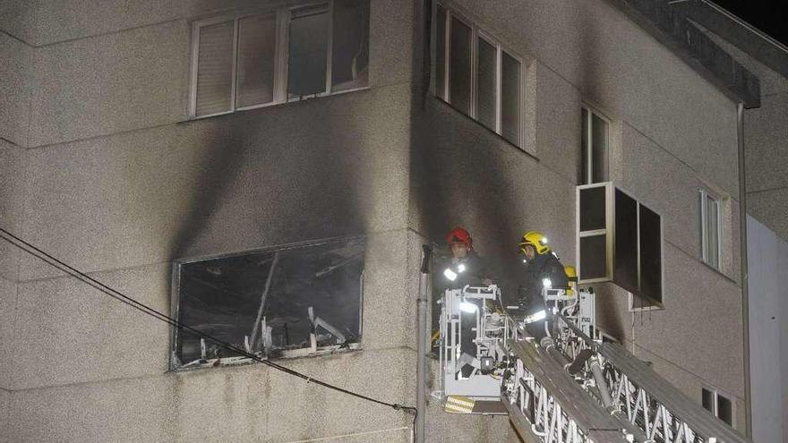 Dos bomberos hacen labores de extinción por el incendio de una vivienda en O Birloque.