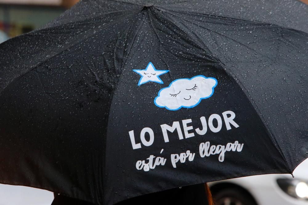 Viandantes tratan de protegerse de la lluvia, en el centro de Vigo