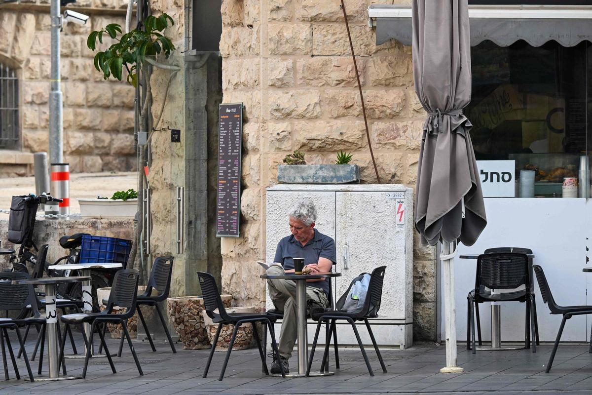 Un hombre lee en la terraza de una cafetería de Jerusalén.