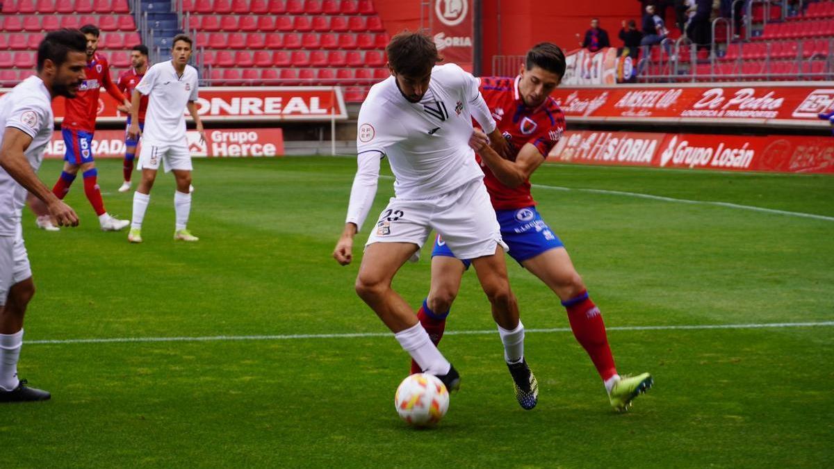 Jorge García protege el balón con su cuerpo mientras es agarrado por su marcador.