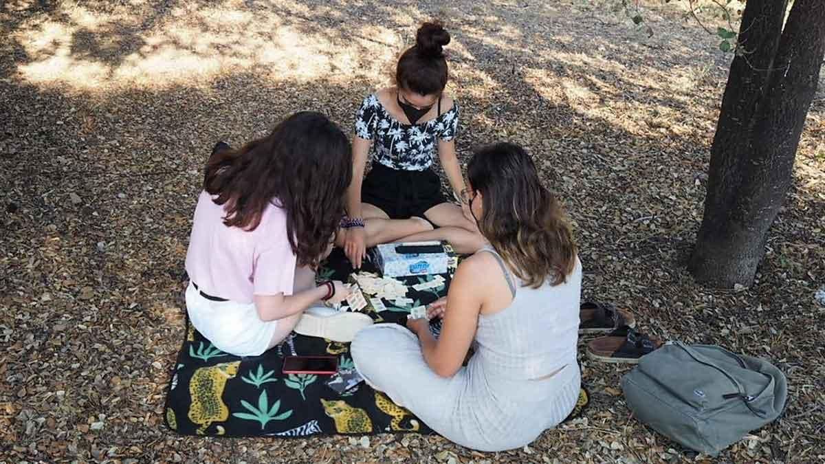 Tres chicas jóvenes quedan cada tarde en un parque de Badalona para jugar a juegos de mesa y mantener la vida social a pesar de las restricciones.