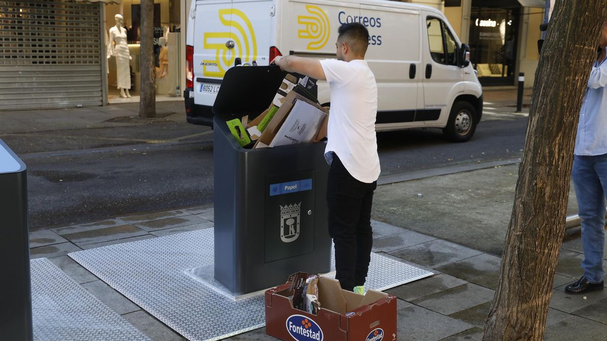 Una persona tira residuos en un contenedor de una calle de Madrid