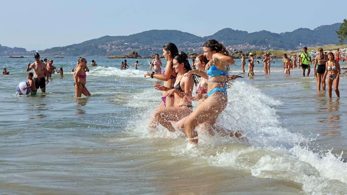 Jóvenes se refrescan en la playa de Samil