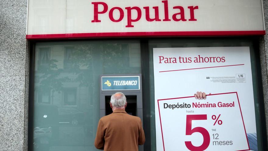 Un cliente saca dinero de un cajero del Popular.