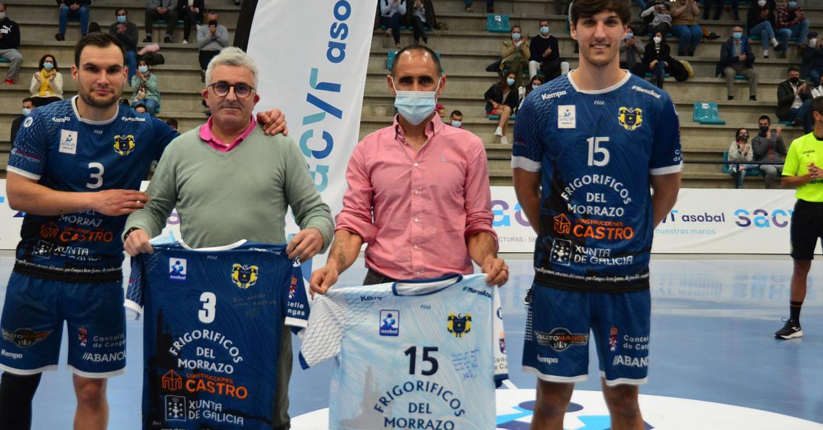 Moisés Simes y David Iglesias, ambos de Bueu, entregan al presidente del Bueu Atlético y al edil de Deportes de Bueu, sendas camisetas con sus dorsales antes del inicio del partido ante Cuenca.