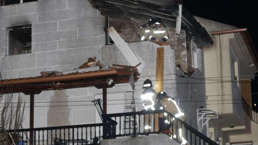 Los bomberos apuntalan la planta superior de la casa tras la explosión.