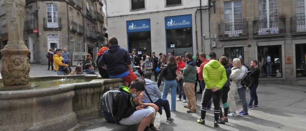 Turistas y peregrinos en la Plaza del Hierro, atendiendo las explicaciones de una guía turística.   | // FERNANDO CASANOVA