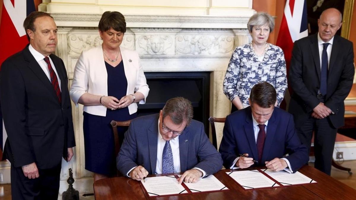 May (2ª por la derecha) y la líder del DUP, Arlene Foster (2ª por la izquierda) observan como los líderes parlamentarios de sus formaciones firman el acuerdo.