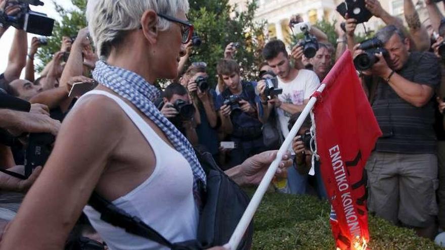 Una manifestante quema una bandera de Syriza. // Reuters