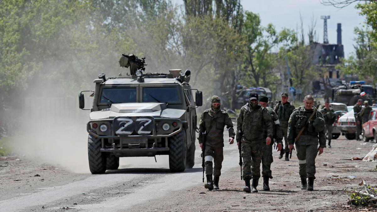 Service members of pro-Russian troops walk along a street in Mariupol