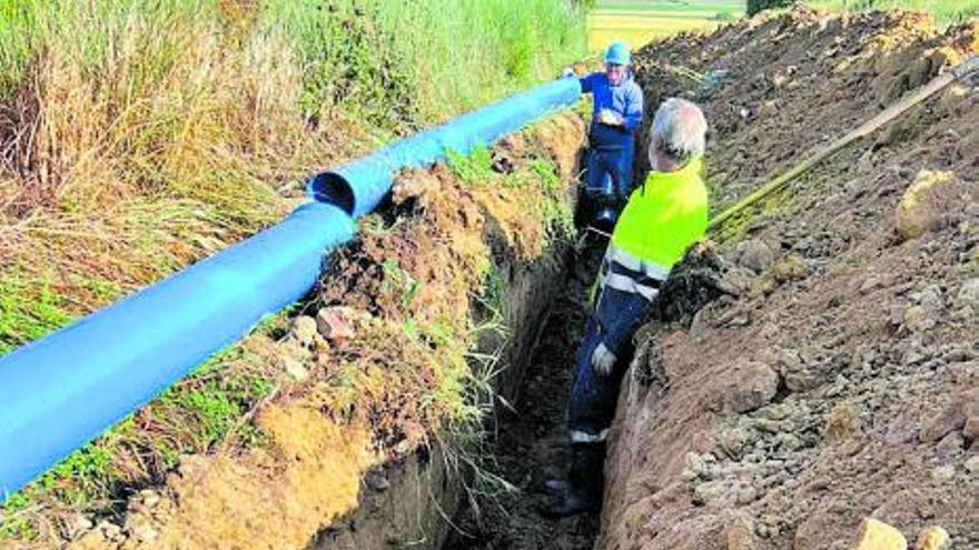 Dos trabajadores instalan las tuberías de agua en Arcenillas. | Ayuntamiento de Arcenillas