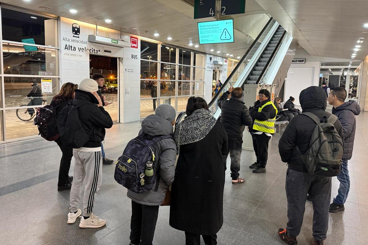 Usuaris de Rodalies a l'estació mirant les pantalles.