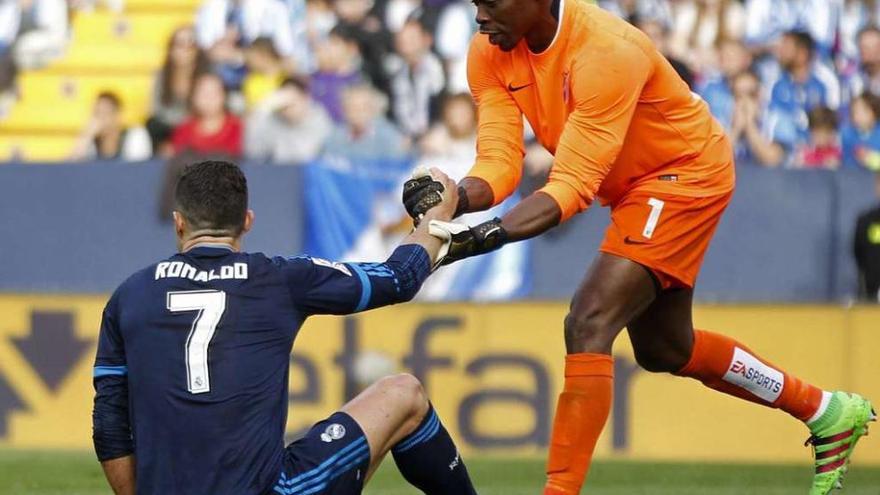 El portero del Málaga, Carlos Kameni, ayuda a levantarse a Cristiano Ronaldo en un momento del choque jugado en La Rosaleda. // Efe