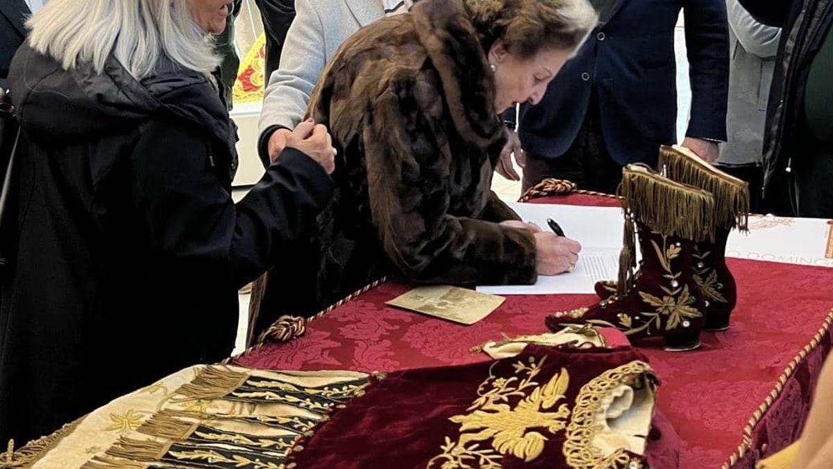 María Jesús García firma el acta de cesión del traje.