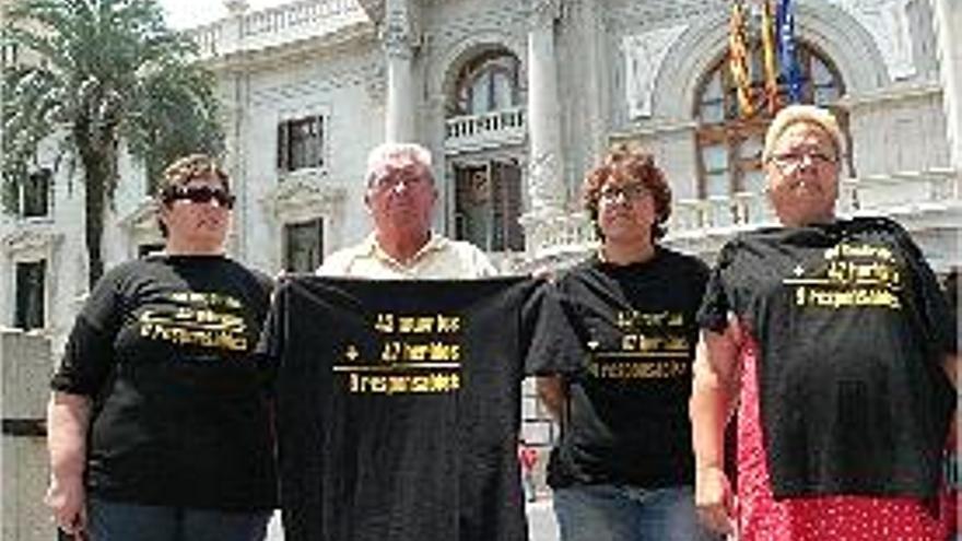 puestas. Cuatro miembros del colectivo, con las camisetas frente al consistorio.