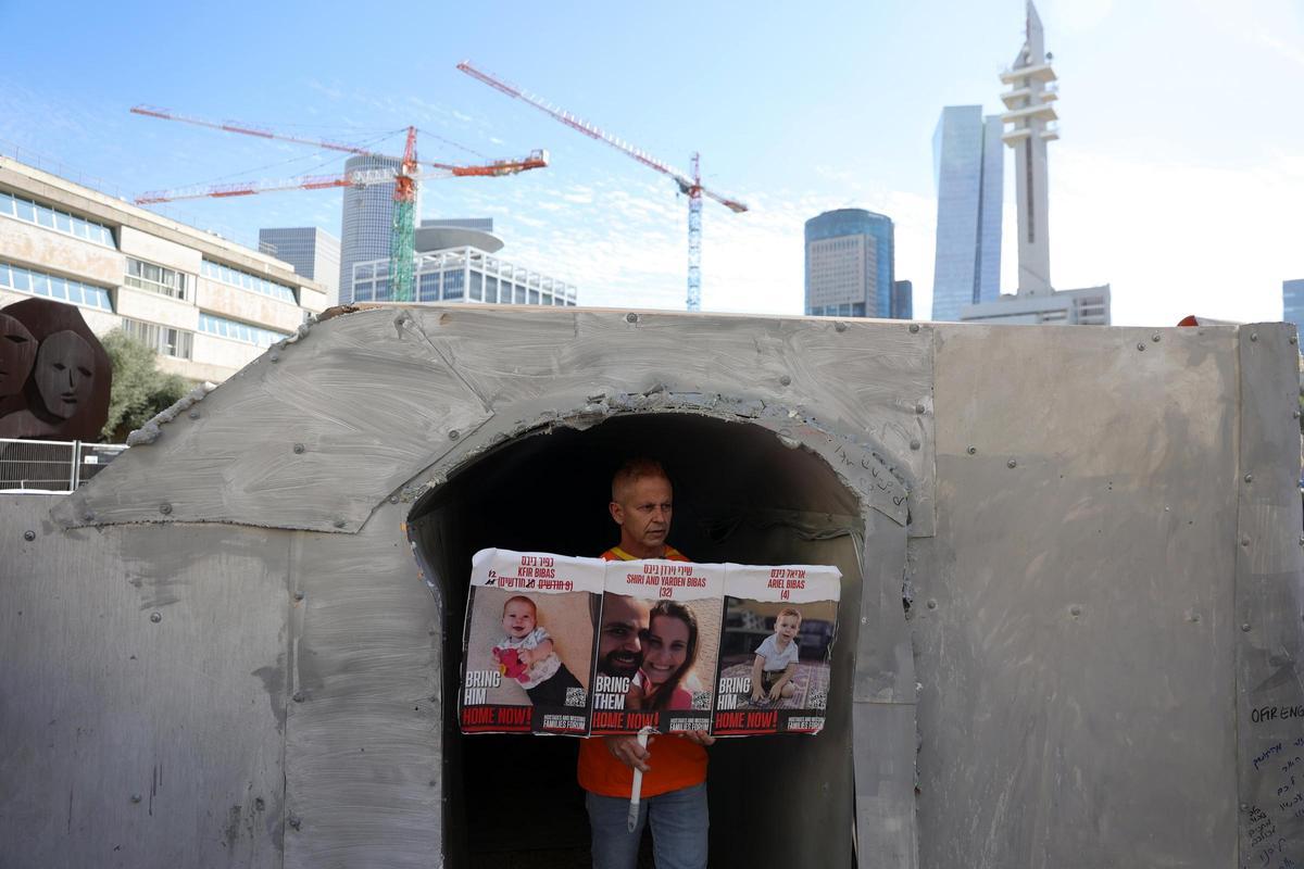 Un familiar de los Bibas muestra un cartel con los rostros de los secuestrados. El padre, Yarden, fue liberado el pasado 1 de febrero.
