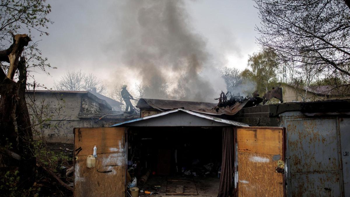 Un bomber intenta apagar un incendi en un garatge provocat per un bombardeig rus a Khàrkiv