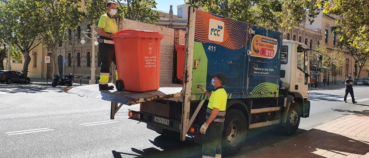 Dos operarios recogen un contenedor de aceite doméstico