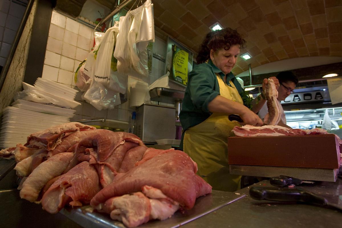Una carnicera prepara un trozo de panceta en un puesto del mercado de La Boqueria de Barcelona, en una imagen de archivo.